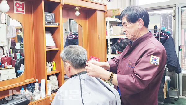 명절 전 두발정리를 하러 온 손님의 머리카락을 다듬고 있는 문학의 대표.