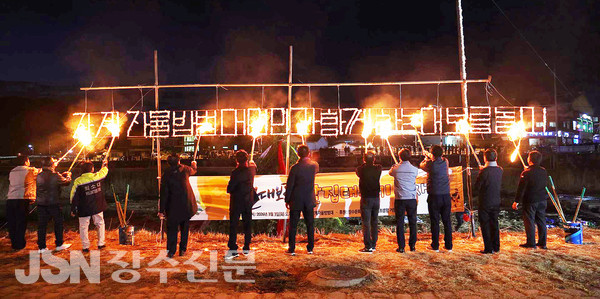 '장계자율방범대 면민과 함께 하는 대보름놀이'가 적힌 솜글자에 불을 붙이고 있다.